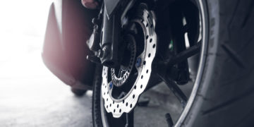 Closeup disc brake of a scooter. Aluminum alloy wheel of motorcycle. Steel rims. Mag wheels of motorbike.