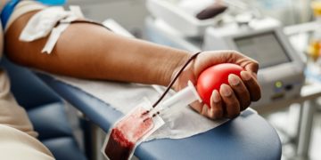 Mulher aperta bola vermelha enquanto doa sangue