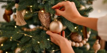 Mão feminina decorando árvore de Natal